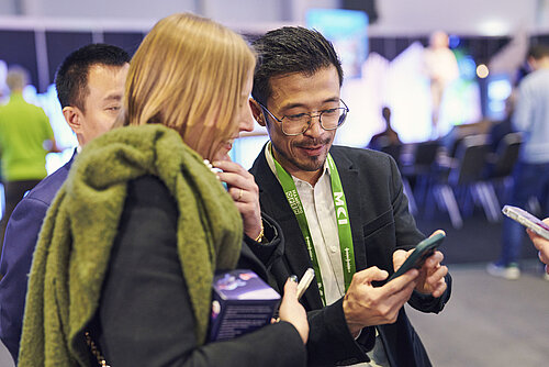 Visitors look at a smartsheet together and chat.